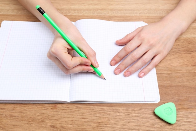 Les mains humaines avec l'écriture au crayon sur papier et effacer le caoutchouc sur fond de table en bois