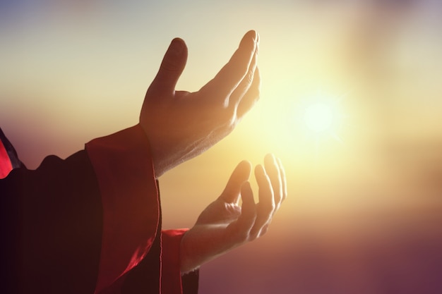 Les mains humaines de silhouette ouvrent la paume vers le haut au coucher du soleil. Miséricorde, Humble, Repentir, Réconcilier, Adorer,