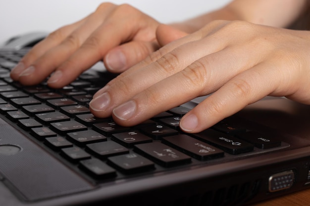 Les mains humaines tapent du texte sur un clavier d'ordinateur portable noir