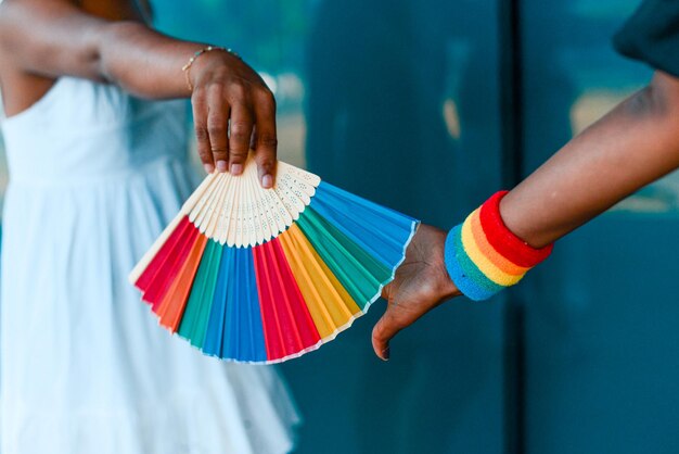 Photo des mains humaines tiennent un ventilateur et un bracelet de fierté lgbtq