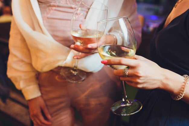 Des mains humaines avec des verres de vin rouge qui sonnent sur la table servie.