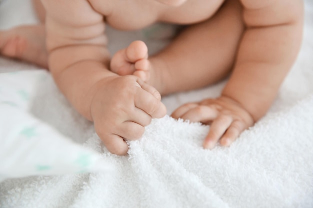 Mains et jambes de bébé dans un lit blanc