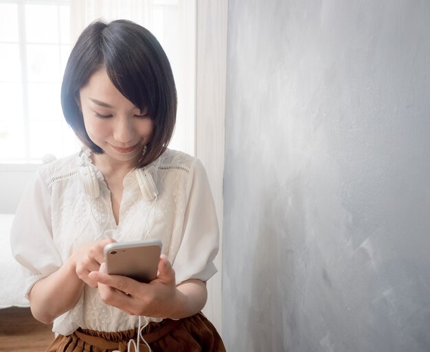 Les mains de la jeune femme asiatique tenant un téléphone portable