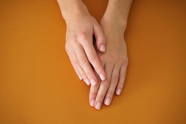 Mains D'une Jeune Femme Avec Une Belle Manucure Sur Fond Beige. Manucure Féminine. Fermer.