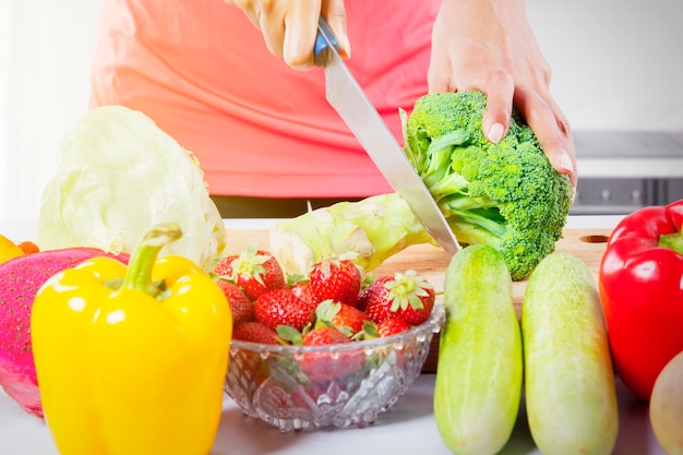 Mains de jeune femme coupant un brocoli frais