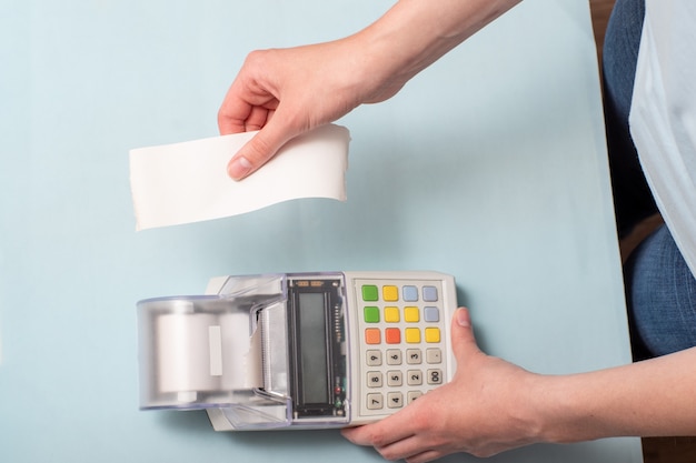 Photo les mains d'une jeune femme déchirant un chèque d'une caisse enregistreuse après l'achat d'un produit