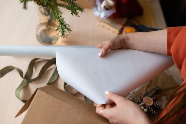 Photo mains de jeune femme emballant des cadeaux de noël photo sans visage recadrée