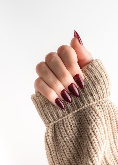 Mains d'une jeune femme avec une manucure rouge foncé sur les ongles