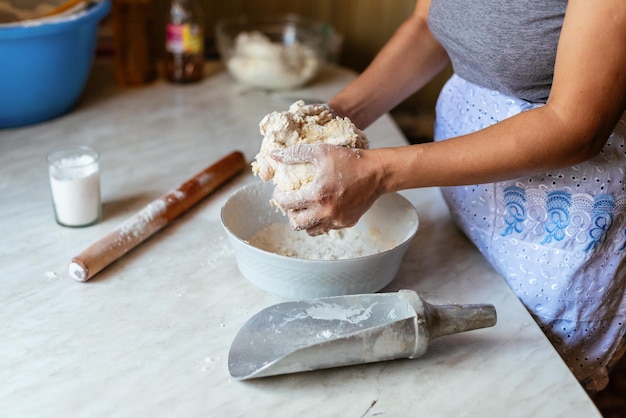 Mains d'une jeune femme pétrissant la pâte pour faire du pain ou de la pizza à la maison Production de produits à base de farine Faire de la pâte par des mains féminines