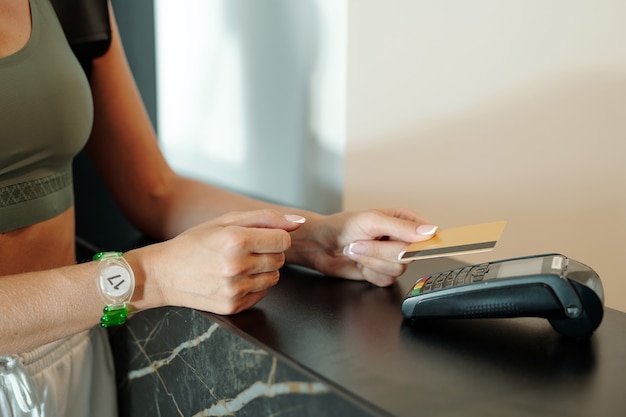 Photo mains de jeune femme tenant une carte de crédit sur un terminal de paiement