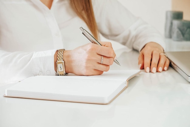 Mains de jeune femme tenant un stylo et écrivant