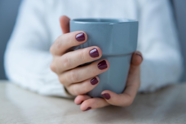 Mains d'une jeune femme tenant une tasse