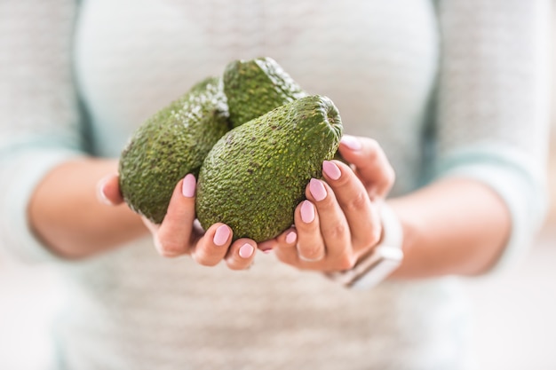 Les mains d'une jeune femme tiennent un avocat frais.