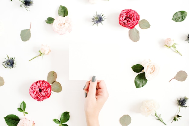 Les mains de la jeune fille avec du papier vierge sur cadre floral avec des boutons de fleurs rose rouge et beige sur blanc