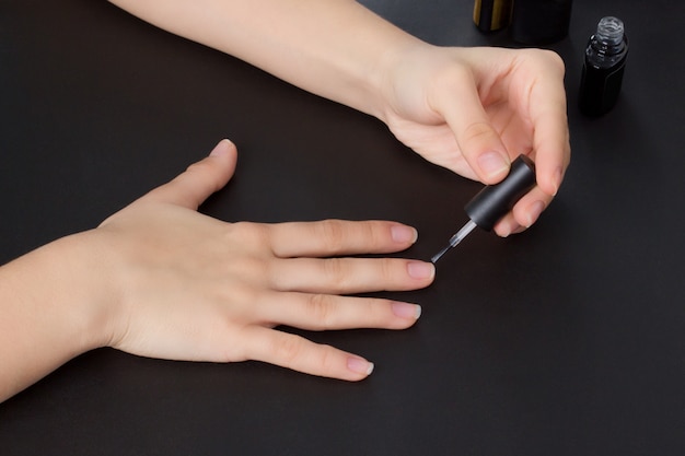 Les mains d'une jeune fille font une manucure avec un revêtement de gomme laque et un renforcement des ongles