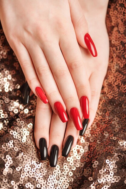 Photo les mains d'une jeune fille avec une manucure rouge et noire sur les ongles