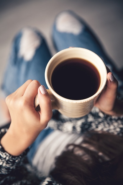 Mains de la jeune fille tenant une tasse de café