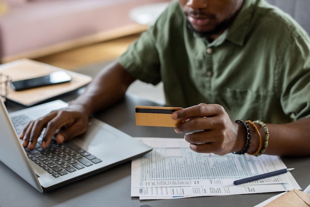 Mains de jeune homme avec carte de crédit en appuyant sur les touches du clavier de l'ordinateur portable