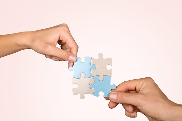 Mains joignant des pièces de puzzle sur fond bleu
