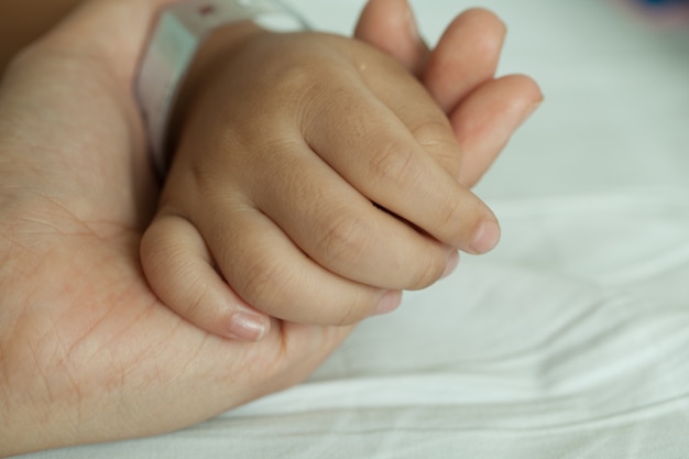 Mains de littel boy et les mains de la mère, le code-barres du bracelet dans le lit d&#39;hôpital