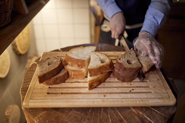 Mains mâles coupant du pain de blé sur la planche de bois, mise au point sélective.