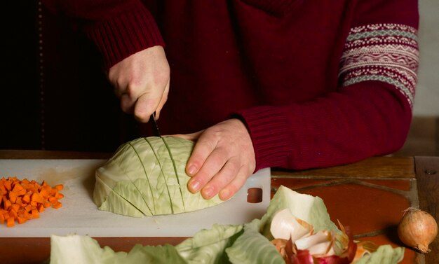 Mains mâles coupent les légumes chou carotte oignon