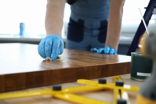 Mains mâles dans des gants en caoutchouc bleu sur table d'huile