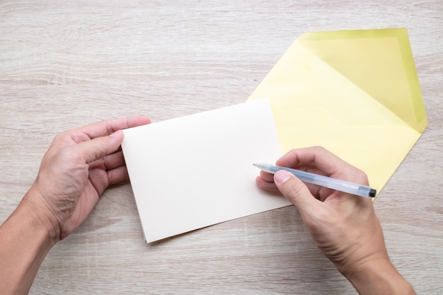 Mains mâles écrivant des cartes vides sur table en bois.