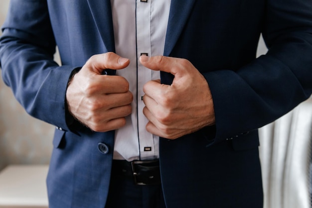 Mains mâles sur un gros plan de veste bleue L'homme ajuste sa veste bleue