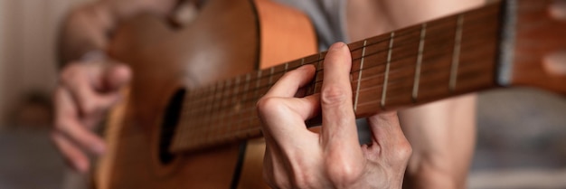 Mains mâles d'un homme de race blanche senior âgé tenant et jouant de la guitare classique se bouchent à la maison des guitaristes sans visage non professionnels jouent de la musique amateur passe-temps domestiques et bannière de loisirs