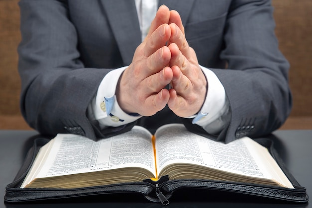 Les mains mâles jointes se trouvent sur une sainte bible ouverte close up