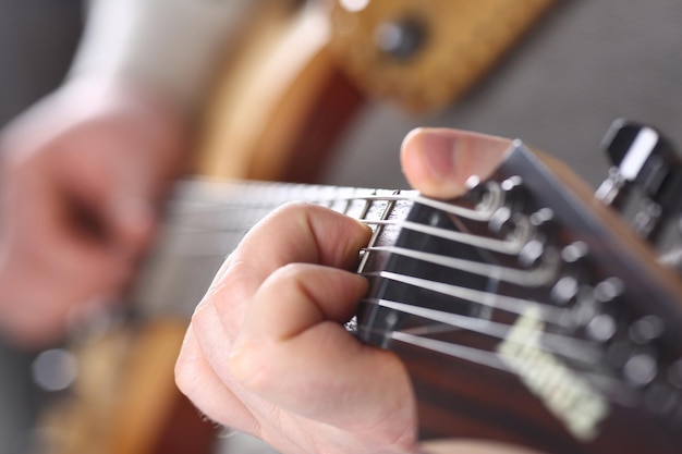 Mains mâles tenant et jouant de la guitare en bois