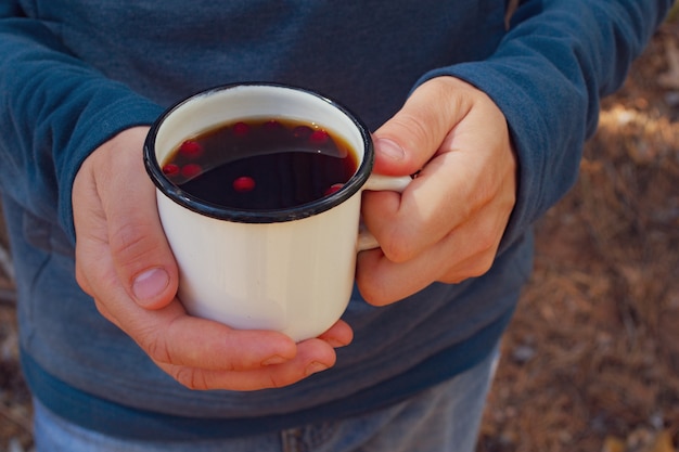 Mains mâles tenant une tasse de thé aux baies