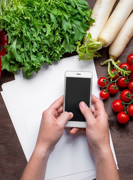 Mains mâles tiennent un smartphone sur la table de cuisine