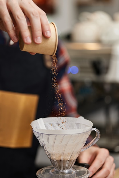 Mains mâles versant du café moulu dans un filtre