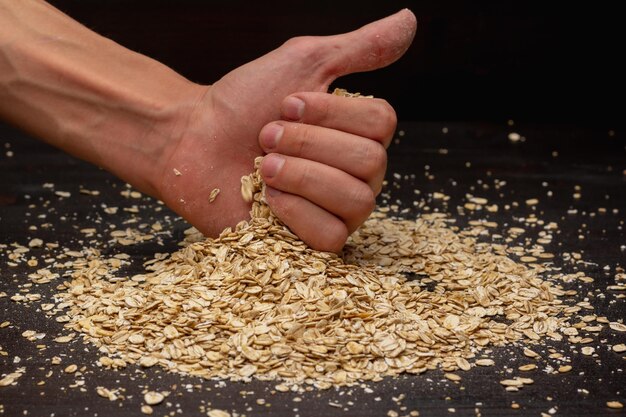 Mains mâles versant du muesli sur fond noir