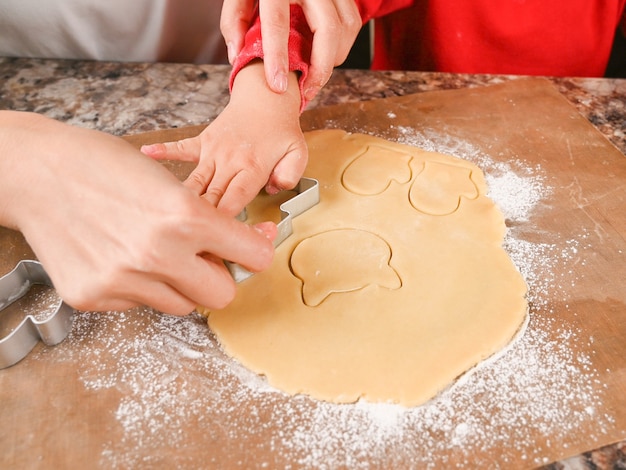 Les mains de maman et de l'enfant fabriquent un moule pour les biscuits du Nouvel An