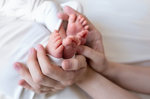 Les mains de maman et papa tiennent les petites jambes de leurs deux nouveau-nés jumeaux.