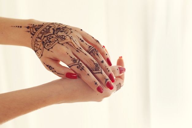 Mains manucurées rouges avec Mehndi