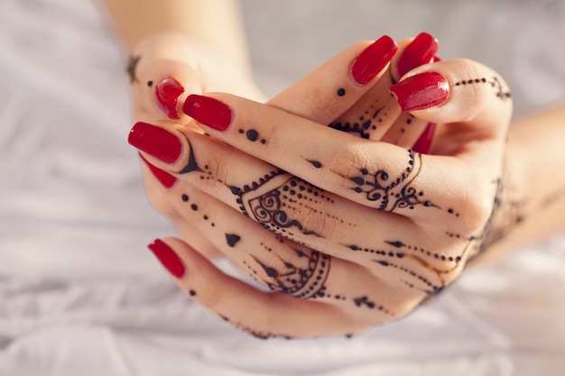 Mains manucurées rouges avec Mehndi