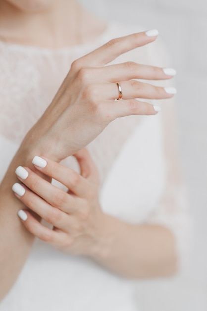 Les mains de la mariée dans une robe de mariée blanche se bouchent