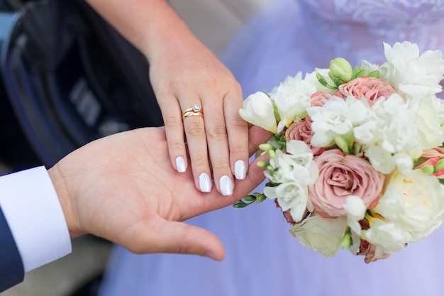 Mains de la mariée et du marié avec des anneaux sur le bouquet de mariage Concept de mariage