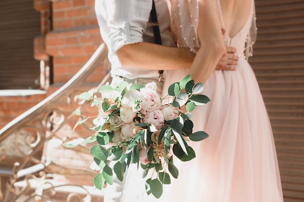 Mains de la mariée et du marié avec bouquet de fleurs de mariage. photographie d'art.