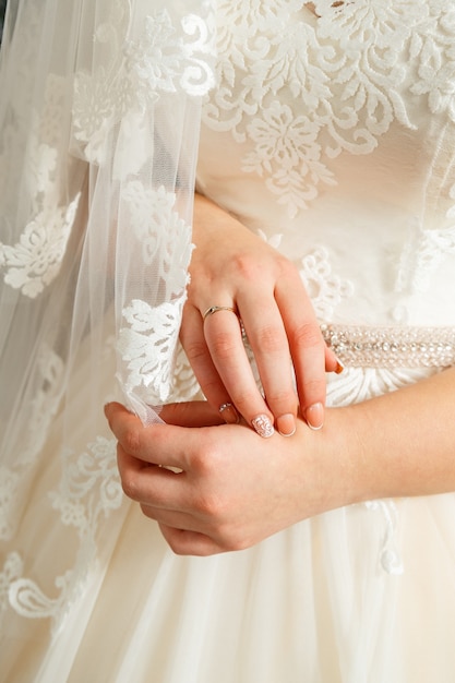 Les mains de la mariée se sont croisées sur une robe de mariée blanche