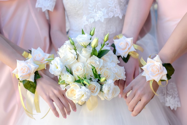 Mains de la mariée et de ses demoiselles d'honneur avec un bouquet