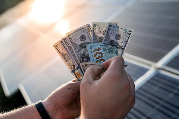 Mains masculines avec des billets en dollars contre des panneaux solaires