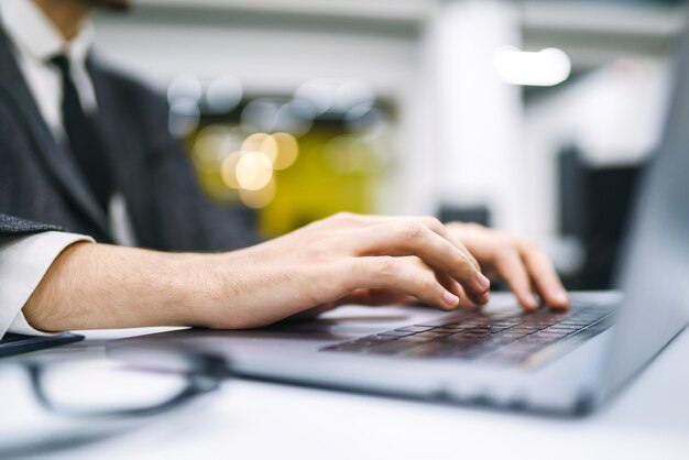 Mains masculines sur le clavier. L'homme d'affaires travaille sur un ordinateur portable et navigue sur Internet, concept de travail en ligne.