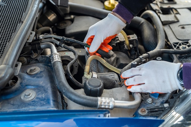 Des mains masculines avec une clé réparent le moteur dans le capot ouvert de la voiture. Concept de service de voiture