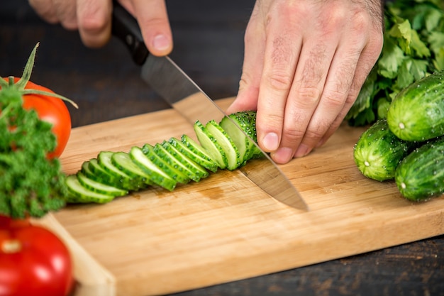 Mains masculines coupant des légumes pour la salade