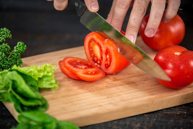 Mains masculines coupant des légumes pour la salade